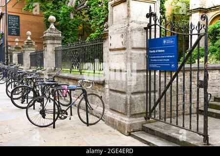 Oxford, Inghilterra - Giugno 2021: Fila di biciclette fissata a portabiciclette fuori dall'entrata del college della Facoltà di Storia nel centro di Oxford Foto Stock