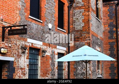 Whitchurch, Hampshire, Inghilterra - 2021 agosto: Ombrellone davanti a uno dei vecchi edifici che fanno parte della distilleria Bombay Sapphire Gin Foto Stock