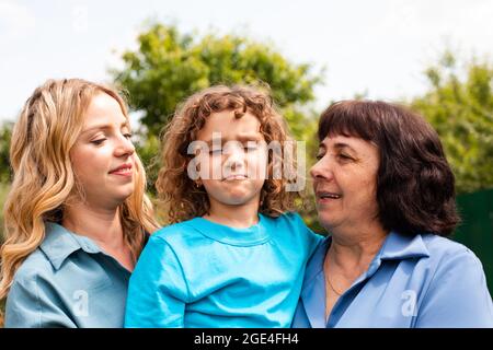 Ragazza carina che abbraccia madre e nonna all'aperto Foto Stock