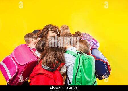 Gli scolari stanno accatastando le mani insieme sullo sfondo giallo Foto Stock