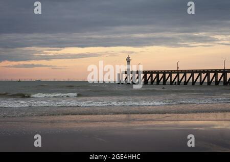 Splendido tramonto dietro il molo all'ingresso del porto di Blankenberge, nelle Fiandre Occidentali, in Belgio. Foto Stock
