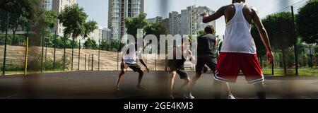 Sportivo che gioca a streetball con persone multietniche su un parco giochi all'aperto, banner Foto Stock
