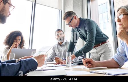 Capo mentore maschile che discute il progetto con la riunione del team nella sala riunioni. Foto Stock