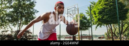 Giovane uomo afroamericano che gioca a basket all'aperto, banner Foto Stock
