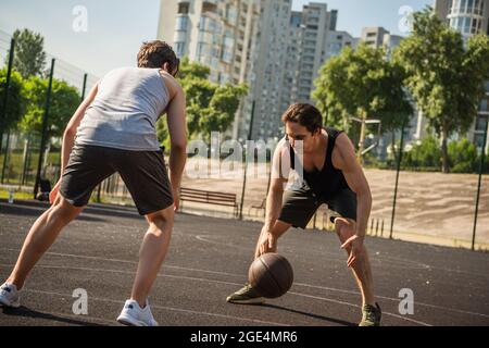 I giovani amici giocano a basket nel parco giochi all'aperto Foto Stock