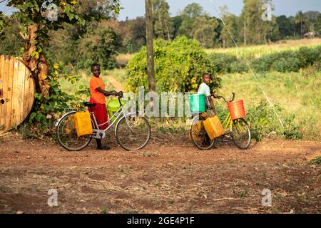 Mvomero, Washington, Tanzania. 16 agosto 2021. Astelia Lawrence e Grace John, residenti all'orfanotrofio EMFERD (Eric Memorial Foundation for the Education and Rehabilitation of the Disabled) a Mvomero, Tanzania, spingono la loro bicicletta per raccogliere acqua.due fonti di acqua, un fiume e un pozzo, sono entrambi a oltre un chilometro dal dormitorio delle ragazze. Ogni residente trasporta fino a 20 litri di acqua al giorno per soddisfare le esigenze dell'orfanotrofio. Credit: ZUMA Press, Inc./Alamy Live News Foto Stock