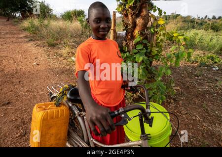 Mvomero, Washington, Tanzania. 16 agosto 2021. Astelia Lawrence, studentessa di EMFERD (Eric Memorial Foundation for the Education and Rehabilitation of the Disabled) orfanotrofio a Mvomero, Tanzania, spinge la sua bicicletta a prendere acqua.due fonti d'acqua, un fiume e un pozzo, sono entrambe a più di un chilometro dal dormitorio delle ragazze. Ogni residente trasporta fino a 20 litri di acqua al giorno per soddisfare le esigenze dell'orfanotrofio. Credit: ZUMA Press, Inc./Alamy Live News Foto Stock