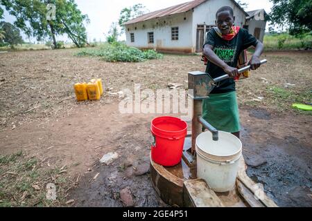 Mvomero, Washington, Tanzania. 16 agosto 2021. Esther Gerard, residente a EMFERD (Eric Memorial Foundation for the Education and Rehabilitation of the Disabled), orfanotrofio a Mvomero, Tanzania, utilizza una pompa manuale per riempire un secchio che porterà all'orfanotrofio.due fonti di acqua, un fiume e un pozzo, sono entrambi a più di un chilometro dal dormitorio delle ragazze. Ogni residente trasporta fino a 20 litri di acqua al giorno per soddisfare le esigenze dell'orfanotrofio. Credit: ZUMA Press, Inc./Alamy Live News Foto Stock