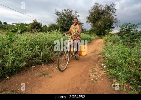 Mvomero, Washington, Tanzania. 16 agosto 2021. Un residente a EMFERD (Eric Memorial Foundation for the Education and Rehabilitation of the Disabled) orfanotrofio a Mvomero, Tanzania, acqua di fetch via bike.due fonti d'acqua, un fiume e un pozzo, sono entrambi a più di un chilometro dal dormitorio delle ragazze. Ogni residente trasporta fino a 20 litri di acqua al giorno per soddisfare le esigenze dell'orfanotrofio. Credit: ZUMA Press, Inc./Alamy Live News Foto Stock