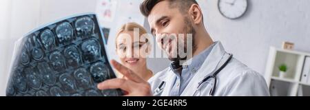 medico positivo guardando cervello mri scansione vicino donna felice, banner Foto Stock