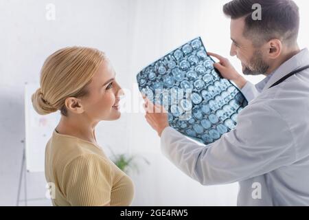 buon medico e paziente che si guardano l'un l'altro vicino alla scansione rm Foto Stock