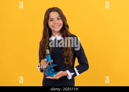 happy kid tenere microscopio per l'istruzione scolastica su sfondo giallo, l'istruzione Foto Stock