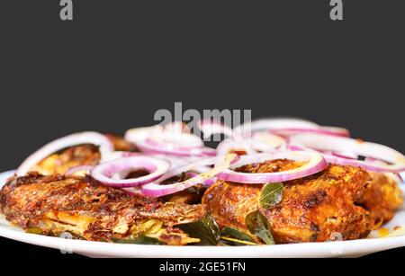 Primo piano immagine di stile Kerala Fish Fry colorato all'interno piatto bianco. Messa a fuoco selettiva Foto Stock