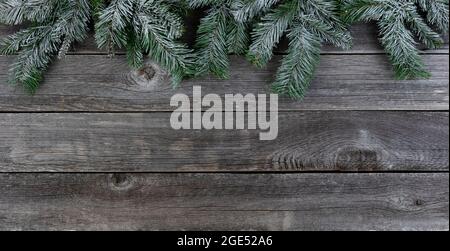 Rami sempreverdi innevati, bordo superiore, su tavole di legno sbiadite per un buon Natale o felice Capodanno concetto di festa Foto Stock