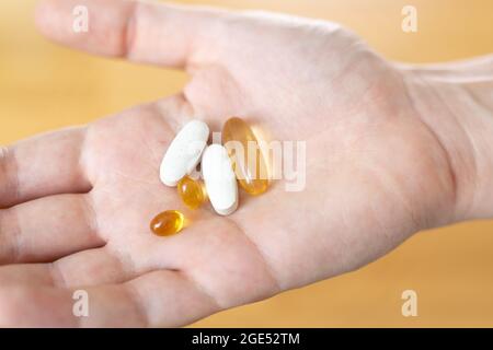 Primo piano di mano con le pillole su di esso. Supplementi con omega, vitamina d, magnesio. Farmaci per il trattamento della malattia Foto Stock