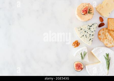 Confine di una selezione di formaggi, fichi, noci e cracker. Vista dall'alto su uno sfondo in marmo bianco con spazio per la copia. Foto Stock