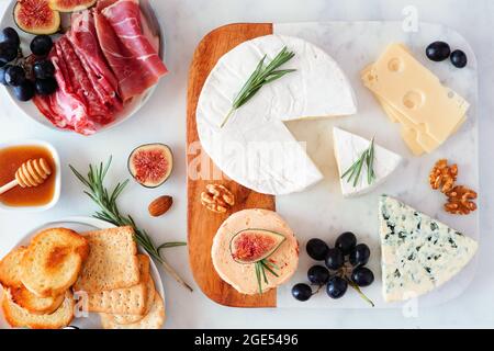 Piatto di formaggi assortiti e salumi. Scenografia da tavolo con vista dall'alto su uno sfondo luminoso. Foto Stock