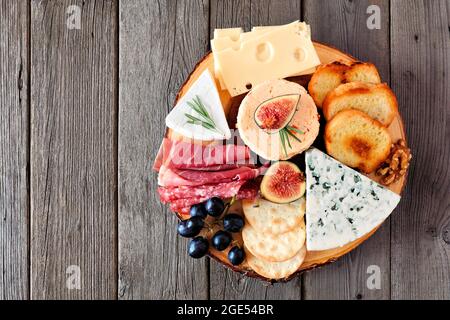 Formaggio a tavola con una selezione di formaggi e carni. Vista dall'alto su uno sfondo rustico in legno. Foto Stock