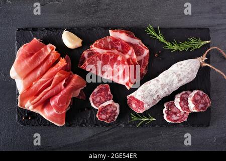 Piatto di antipasti di carne con salsiccia e salumi italiani. Vista sopra su un asse di servizio dell'ardesia. Foto Stock