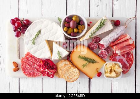 Serve un piatto di carni assortite, formaggi e antipasti. Vista dall'alto su uno sfondo di legno bianco. Foto Stock