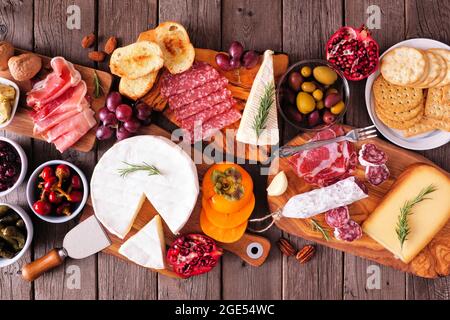 Tavole di salumi di carni assortite, formaggi e antipasti. Tavolo con vista dall'alto su uno sfondo rustico in legno. Foto Stock