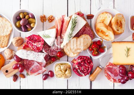 Salumi a bordo di formaggi assortiti, carni e antipasti. Sopra il tavolo scenografico su sfondo di legno bianco. Foto Stock