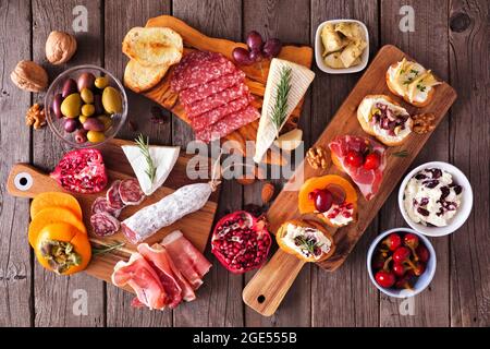 Antipasti di festa con formaggi assortiti, carni e crostini. Vista dall'alto su uno sfondo rustico in legno. Foto Stock