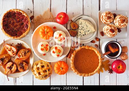 Concetto di cibo autunnale. Selezione di torte, antipasti e dessert. Tavolo con vista dall'alto su uno sfondo di legno bianco. Foto Stock