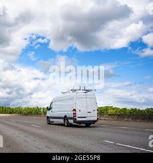 Mini furgone bianco compatto industriale di piccole dimensioni con tetto alto per consegne locali confortevoli e piccole esigenze aziendali in esecuzione sull'ampio highwa multilinea Foto Stock