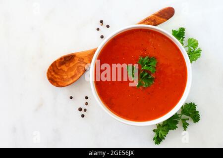 Zuppa di pomodoro fatta in casa. Vista dall'alto, semplice scenario da tavolo su un luminoso sfondo di granito. Foto Stock