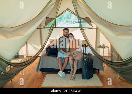 Felice giovane coppia caucasica rilassarsi a letto all'interno della casa glamping dopo l'arrivo Foto Stock