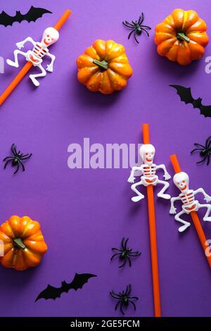 Buon concetto di vacanza di Halloween. Decorazioni di Halloween, zucche, pipistrelli, scheletri su sfondo viola. Disposizione piatta, vista dall'alto, vista dall'alto. Foto Stock