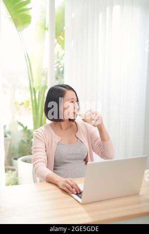 Donna incinta che lavora da casa Foto Stock