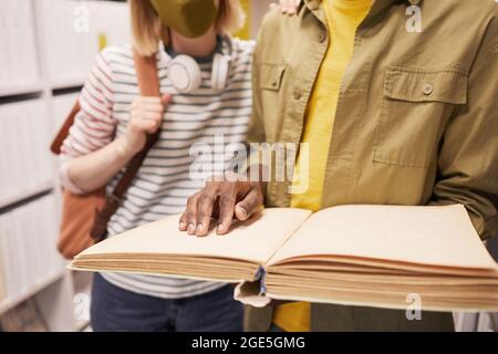 Ritratto ritagliato di studente che aiuta amico cieco in biblioteca, spazio di copia Foto Stock