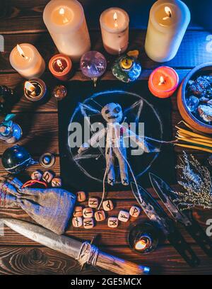 Bambola Voodoo su tavolo di legno con candele e oggetti occulti, vista dall'alto. Sfondo rituale magico e scuro, immagine verticale del poster. Foto Stock