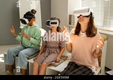 Tre studentesse multirazziali in visori vr che guardano una presentazione in 3d Foto Stock