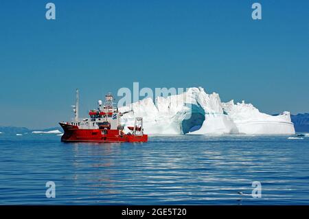 Nave di ricerca rossa di fronte a iceberg con Loch, luglio, Ilulissat, Disko Bay, Groenlandia, Danimarca Foto Stock