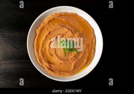 Famosa cucina araba tradizionale - fagioli di fava sbucciati purè pianura in una ciotola bianca su sfondo marrone scuro. Vista dall'alto. Fallo Mudammas Foto Stock