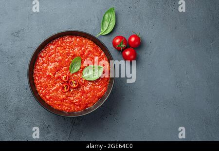Salsa di pomodoro con pepe e basilico fresco su sfondo scuro. Foto Stock