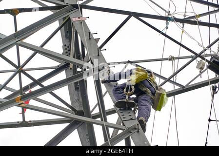 Uomini che lavorano in quota, ristrutturando i piloni elettrici, Inghilterra settentrionale, Regno Unito Foto Stock