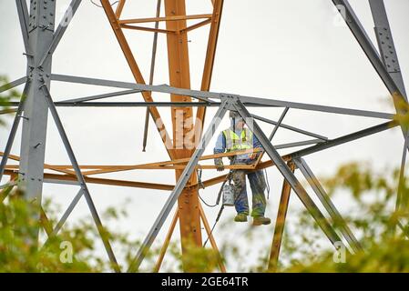 Uomini che lavorano in quota, ristrutturando i piloni elettrici, Inghilterra settentrionale, Regno Unito Foto Stock