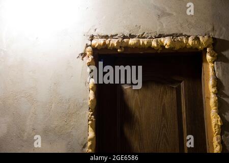 Riparazione in casa. Porte. Schiuma da costruzione. Pareti intonacate Foto Stock