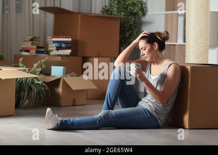 Triste sfratta donna che si muove a casa lamentandosi di sedersi sul pavimento nella notte Foto Stock