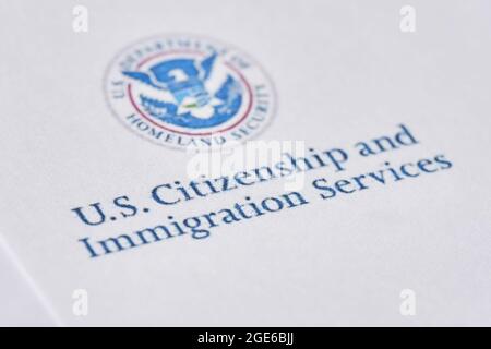 Tashkent, Uzbekistan - 13 agosto 2021: Servizi di cittadinanza e immigrazione degli Stati Uniti. Buste con lettera da USCIS sulla bandiera degli Stati Uniti Foto Stock