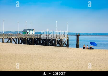 Arcachon (Francia sud-occidentale): Molo di Eyrac e spiaggia con tre persone e un ombrellone Foto Stock