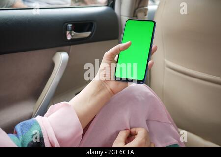 donne tenere a mano smartphone con schermo verde in un'auto Foto Stock