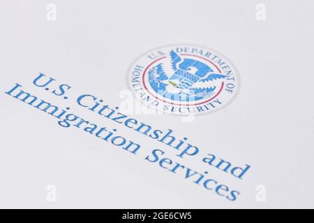 Tashkent, Uzbekistan - 13 agosto 2021: Servizi di cittadinanza e immigrazione degli Stati Uniti. Buste con lettera da USCIS sulla bandiera degli Stati Uniti Foto Stock