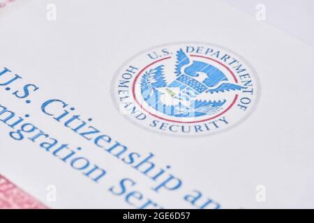 Tashkent, Uzbekistan - 13 agosto 2021: Servizi di cittadinanza e immigrazione degli Stati Uniti. Buste con lettera da USCIS sulla bandiera degli Stati Uniti Foto Stock