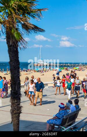 Arcachon (Francia sud-occidentale): Numerosi turisti sulla spiaggia e la passeggiata lungo il lungomare, con il molo Eyrac sullo sfondo. Vacanze Foto Stock