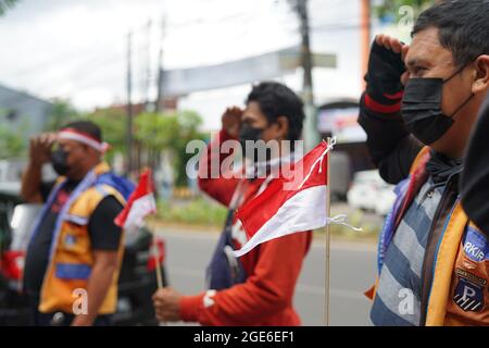 Makassar, Indonesia, 17 agosto 2021. Un certo numero di addetti al parcheggio a Makassar ha celebrato la commemorazione del 76° giorno dell'Indipendenza indonesiana, tenendo una cerimonia virtuale mentre guardava un cellulare che trasmetteva una trasmissione in diretta della cerimonia della bandiera al Palazzo di Stato. Credit: Herwin Bahar/Alamy Live News Foto Stock